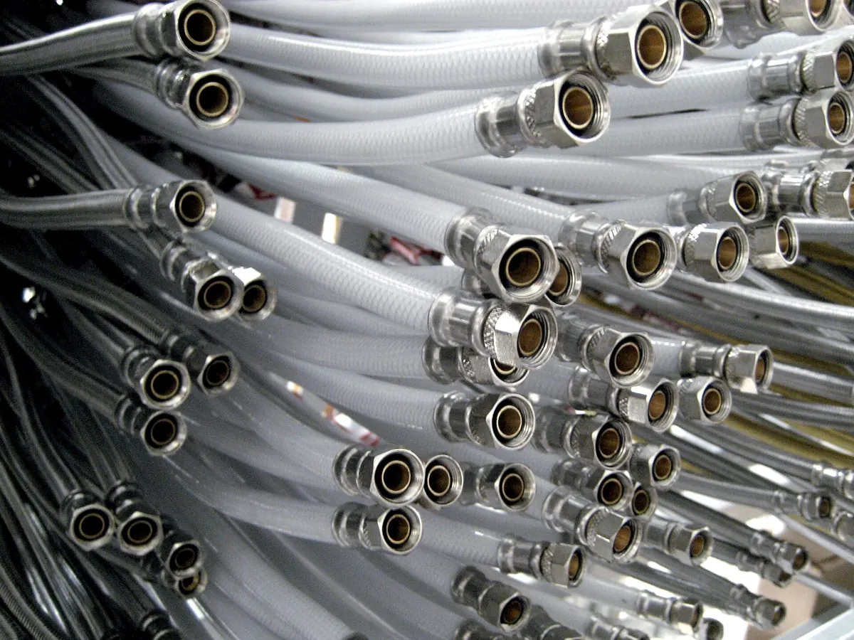 A bin of braided stainless steel faucet supply hoses with chrome nuts